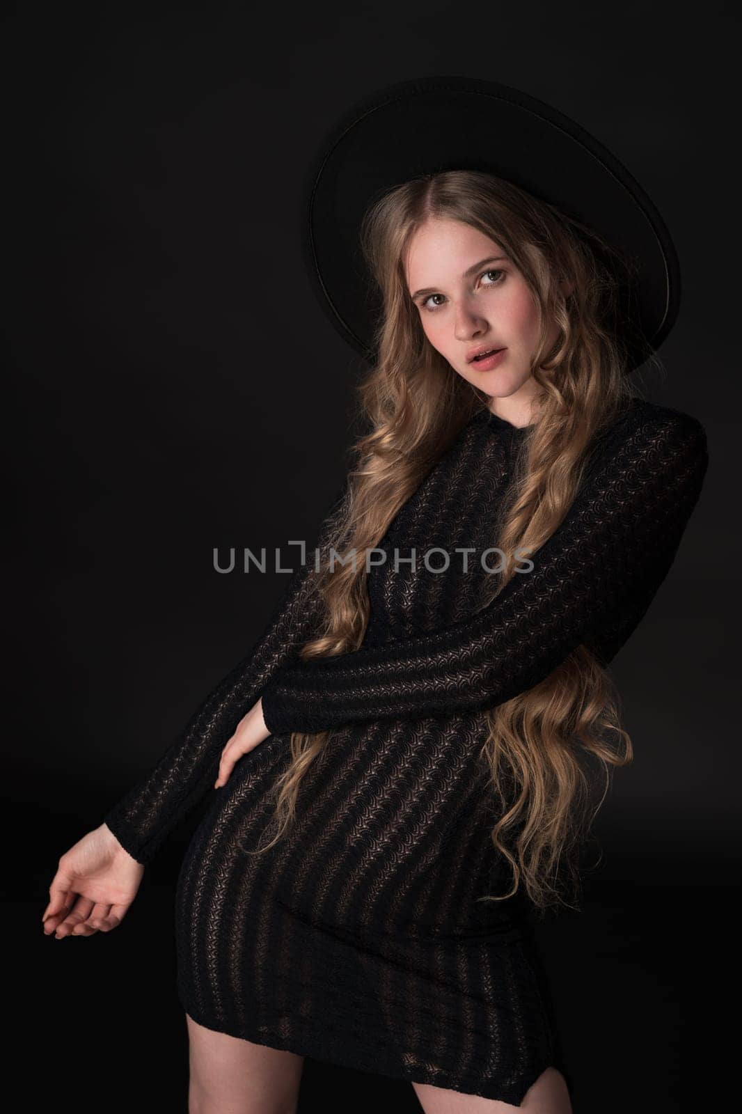 Portrait of blonde model exuding sensuality in relaxed pose on black background, looking at camera by Alexander-Piragis