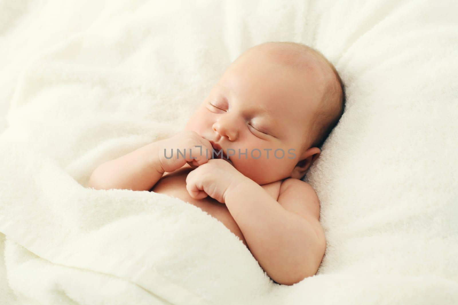 Close up portrait of infant sweet sleeping lying on white bed at home