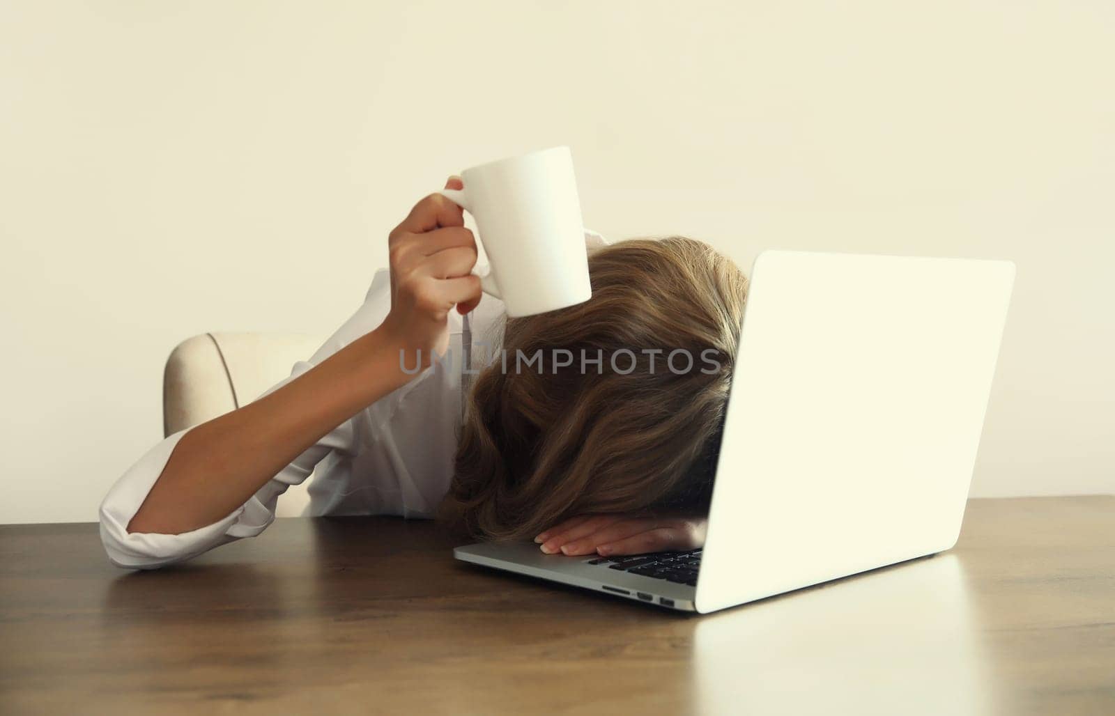 Tired overworked sleepy woman employee holding cup asking to drink extra coffee working with laptop sitting at desk in office in morning