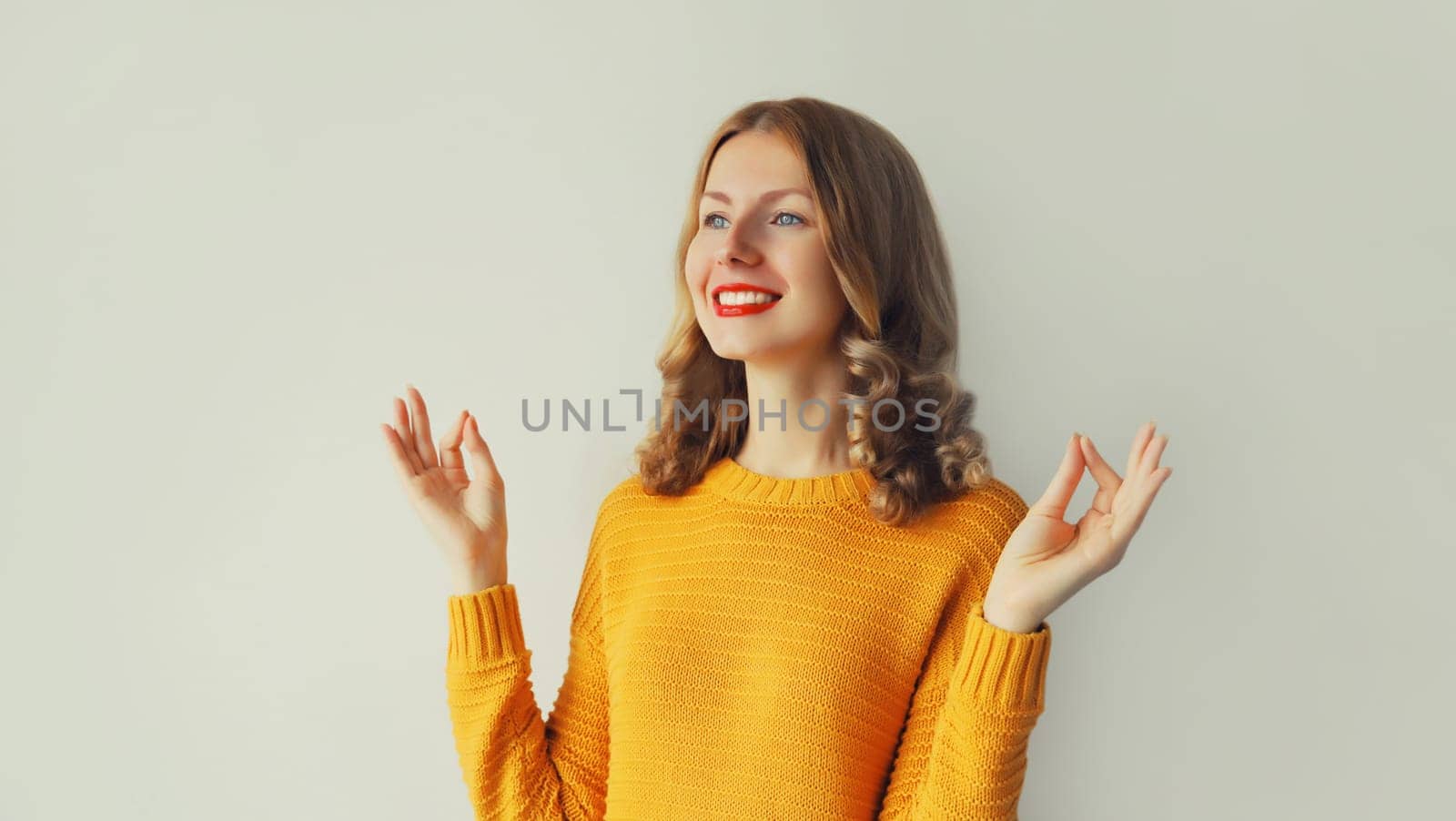 Calm relaxing healthy young woman meditates, practicing yoga on studio background