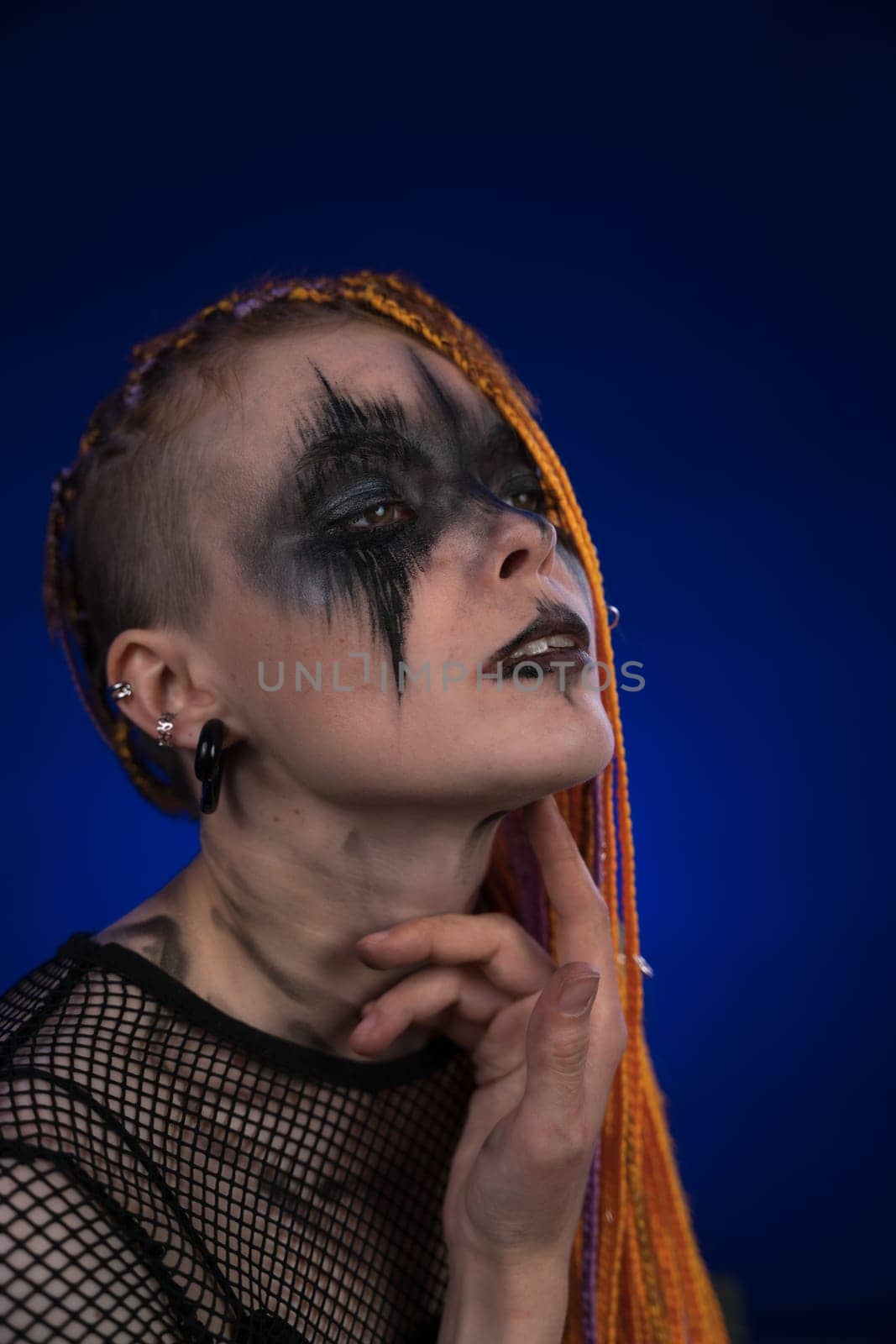 Informal woman with orange color dreadlocks hairstyle and horror black stage makeup painted on face by Alexander-Piragis