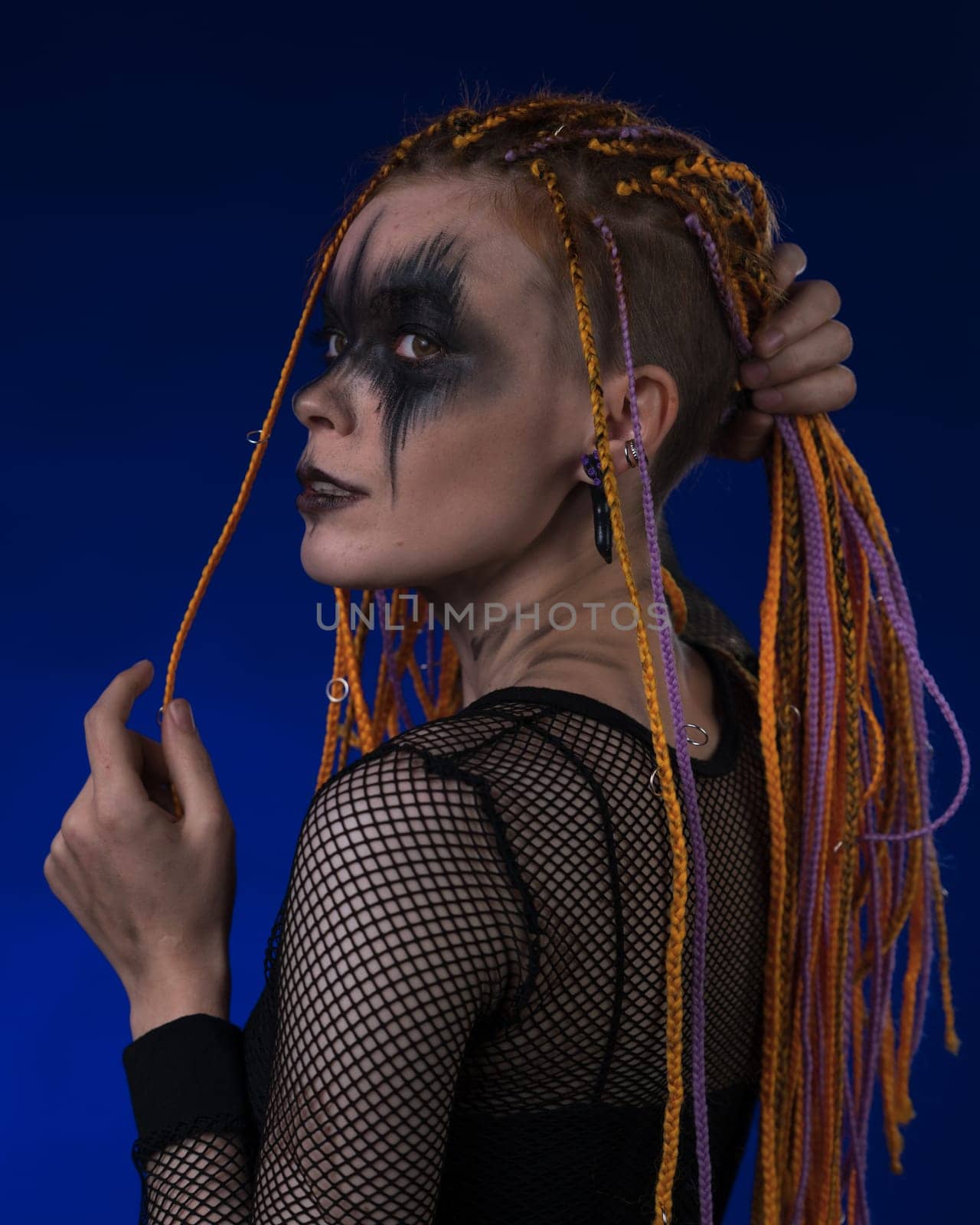 Dramatic portrait of young female with horror stage makeup painted on face and dreadlocks hairstyle by Alexander-Piragis