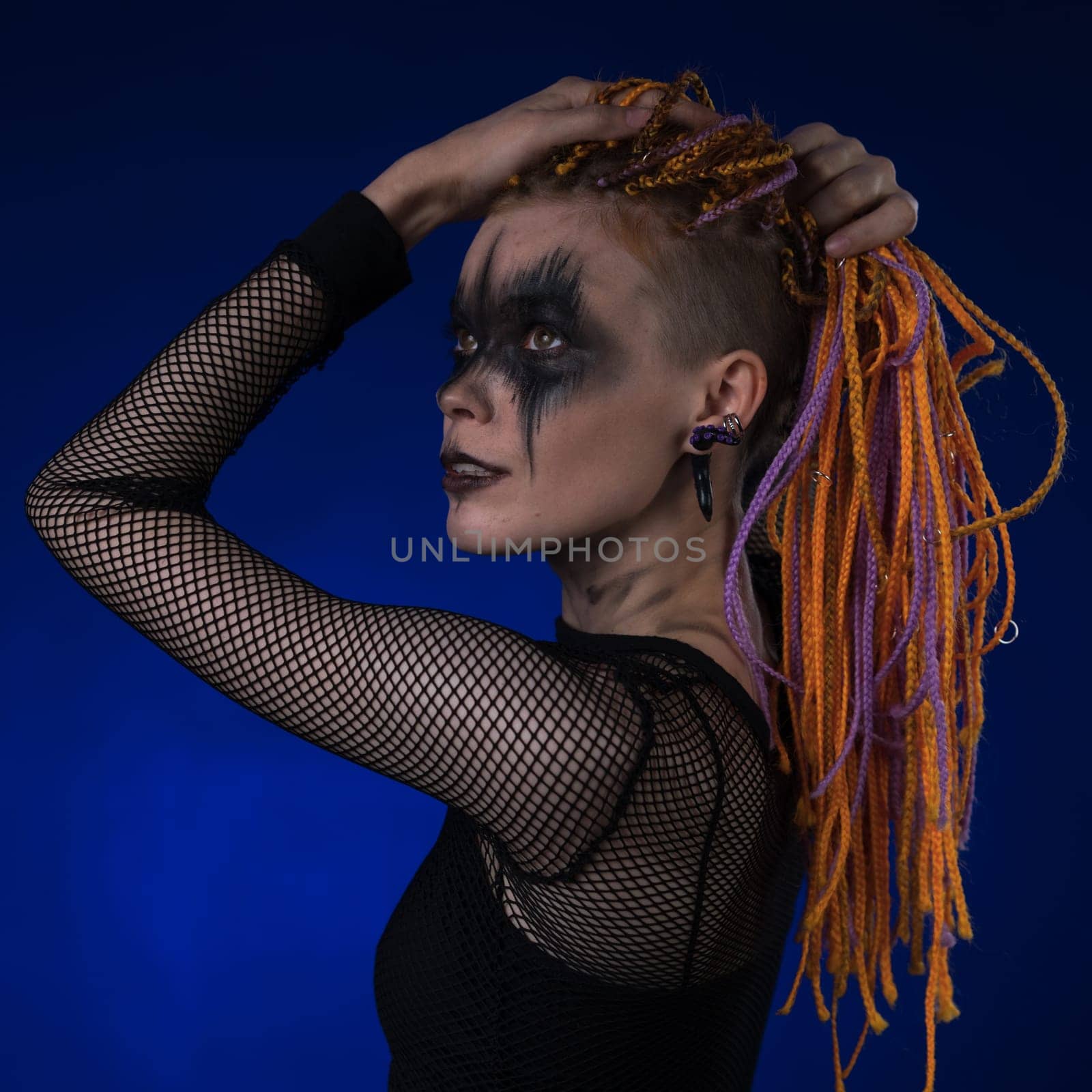 Dramatic portrait of young female with spooky stage makeup painted on face and dreadlocks hairstyle by Alexander-Piragis