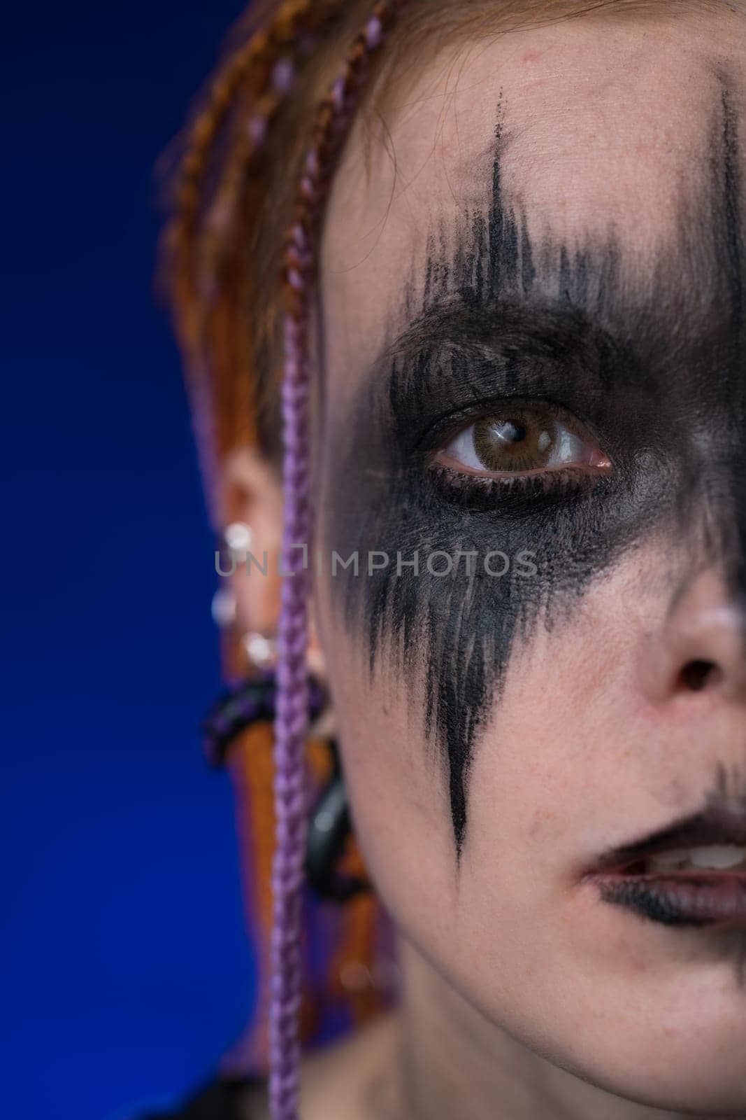 Dramatic portrait of half female face with horror black stage makeup and dreadlocks hairstyle by Alexander-Piragis