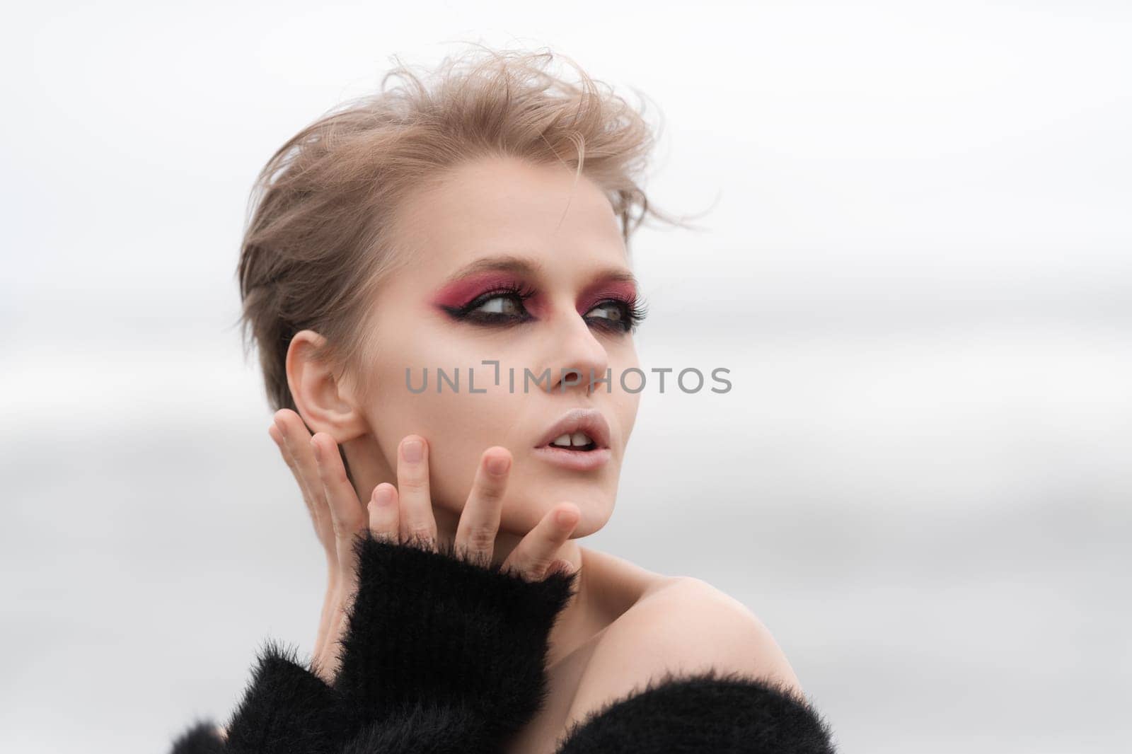 Portrait blonde woman fashion model looking away, posing outdoors on white natural background. Face of Caucasian woman with short hair, bright makeup. Soft selective focus adds to overall dreamy vibe