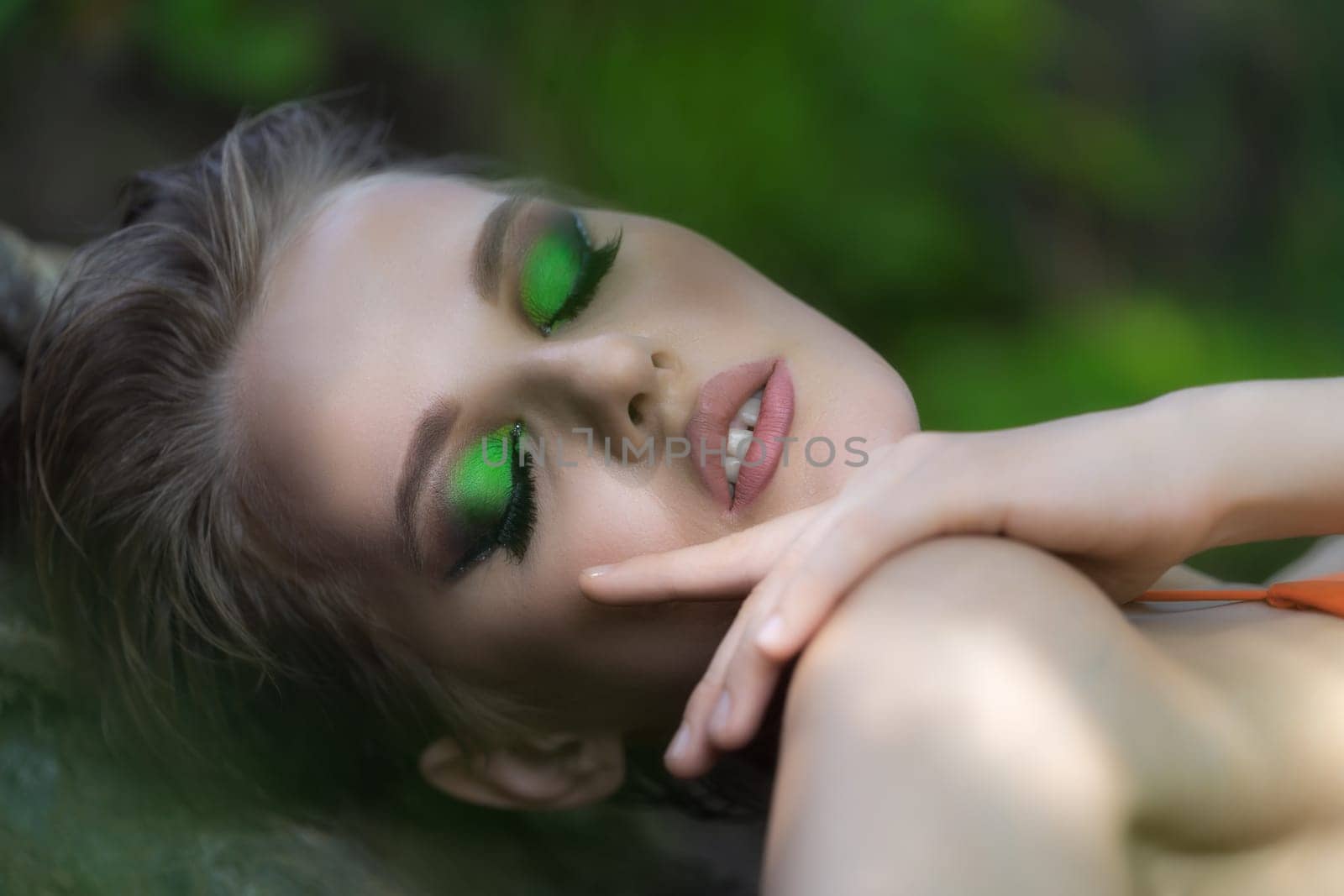 Close-up portrait of European woman with eyes closed relaxation in summer forest, enjoyment outdoors. Sexual face of blonde model with bright make-up and short hair. Selective focus