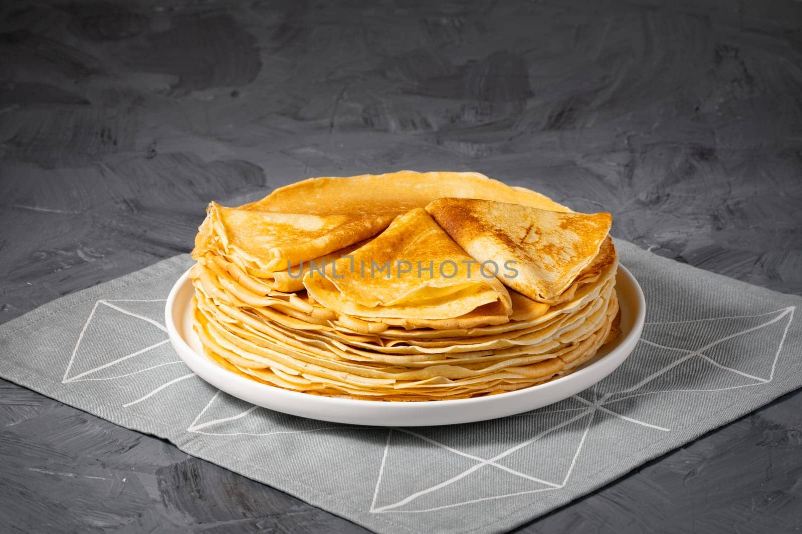 A stack of thin pancakes on a grey table , with copy space for text.