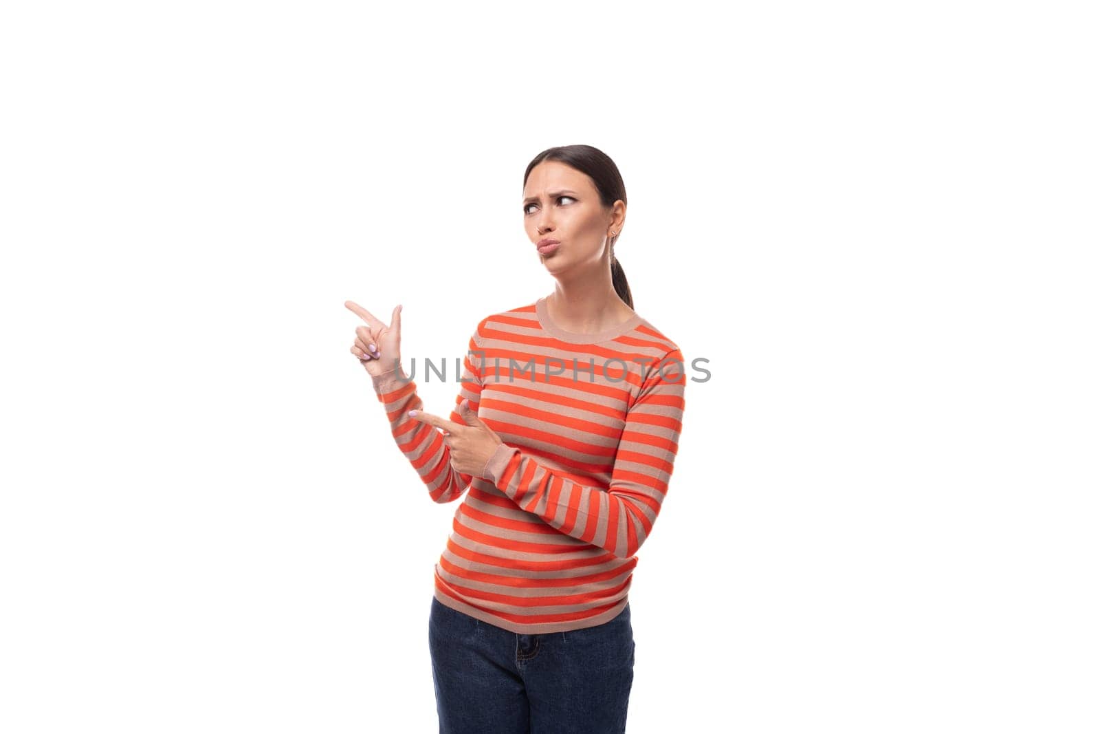 young puzzled brunette lady dressed in a casual striped blouse with surprise holds her hand to the side.