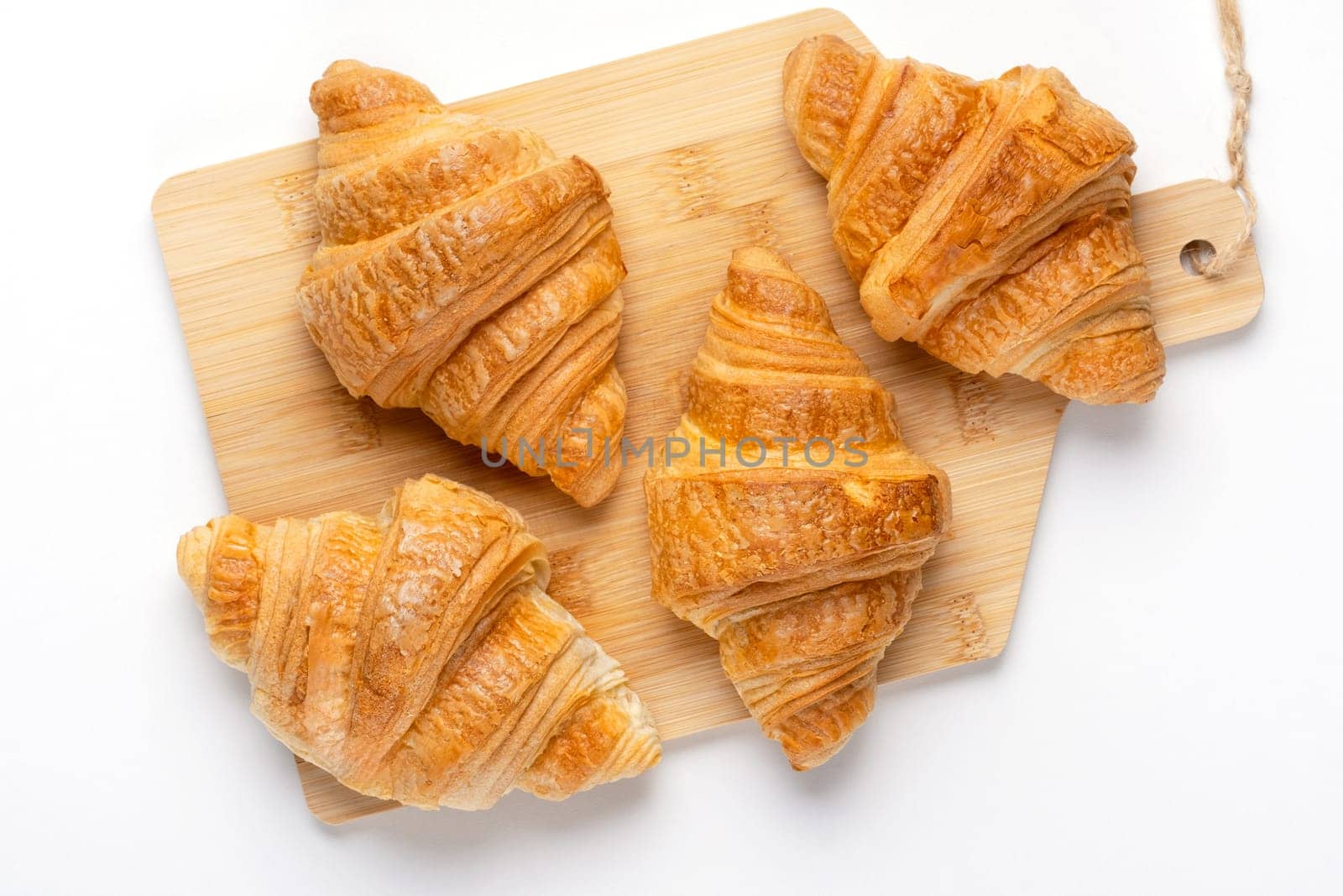 French croissants for breakfast. Freshly baked croissants on cutting board, isolated on white background, top view.