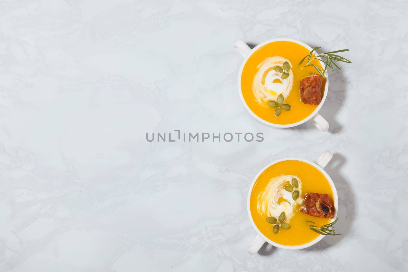 Pumpkin cream soup with smoked pork ribs and cream, top view, with copy space