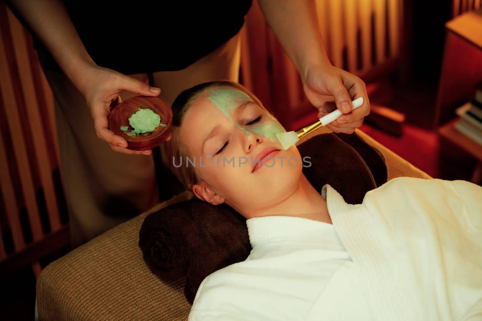 Serene ambiance of spa salon, woman customer indulges in rejuvenating with luxurious face cream massage with warm lighting candle. Facial skin treatment and beauty care concept. Quiescent