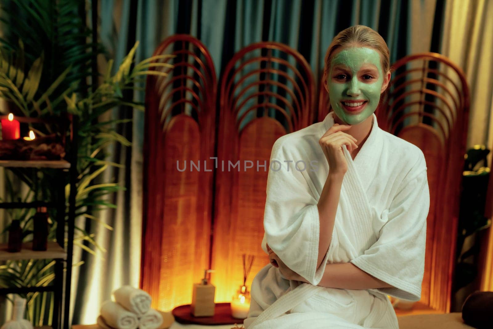 Serene ambiance of spa salon, woman customer indulges in rejuvenating with luxurious face cream massage with warm lighting candle. Facial skin treatment and beauty care concept. Quiescent