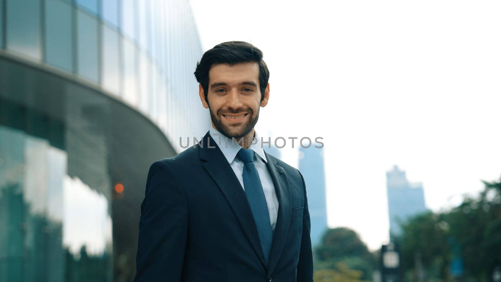 Professional businessman standing at city or park with arm folded. Exultant. by biancoblue