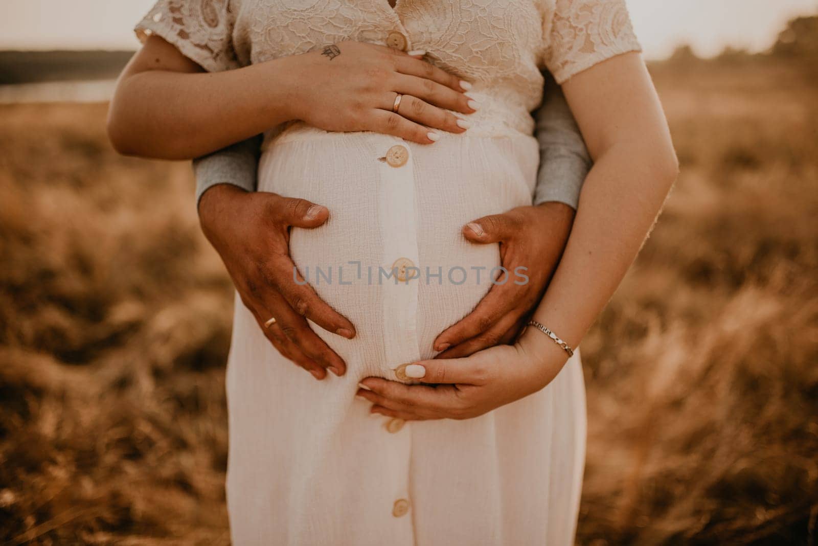 hands of future mother and father clasped pregnant big tummy. by AndriiDrachuk