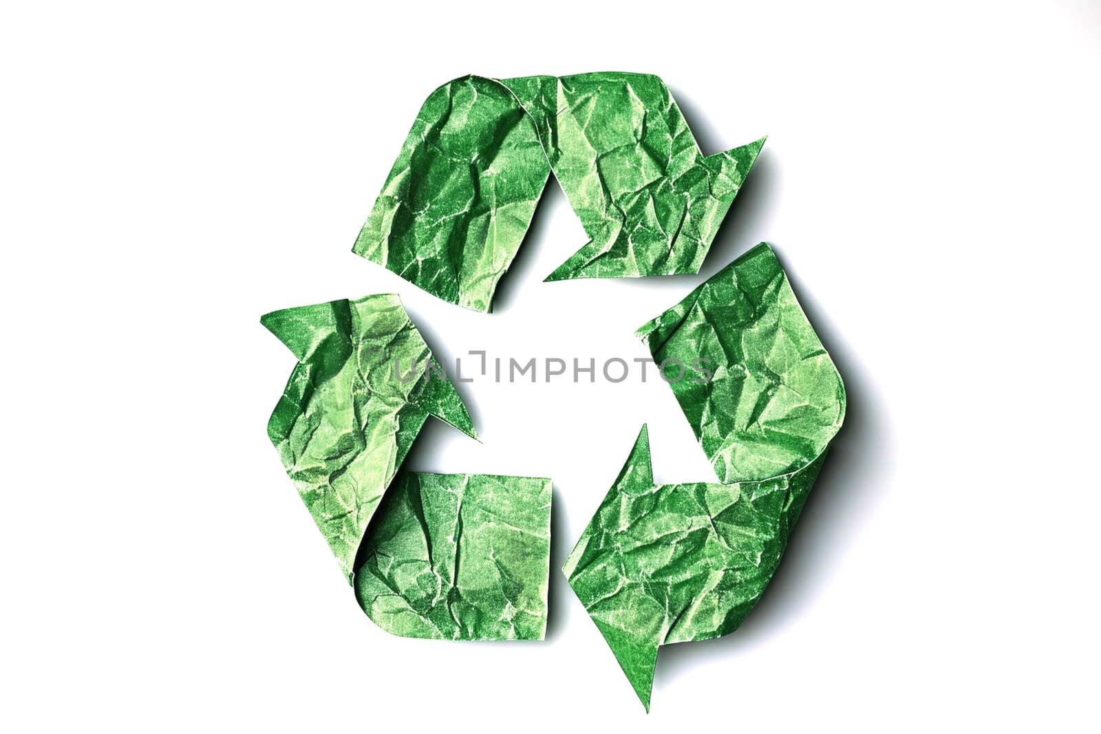 Recycling symbol made of crumpled green paper on a white background. Environmental protection concept.