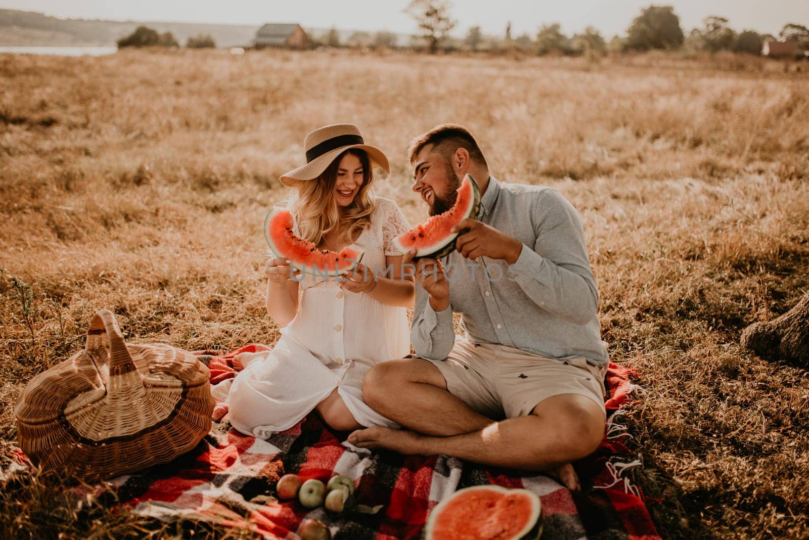 caucasian family with a pregnant woman relaxing in nature picnic eating watermelon laugh having fun by AndriiDrachuk