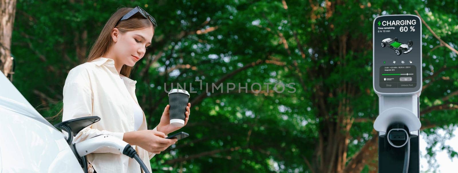 Young woman with coffee and sustainable urban commute by EV electric car recharging at outdoor cafe in springtime garden, green city sustainability and environmental friendly EV car.Panorama Expedient