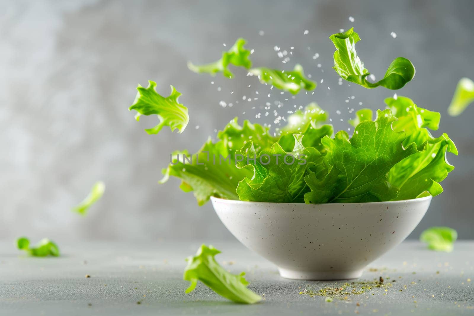 A white bowl filled with lettuce leaves sits atop a wooden table in this simple and minimalist composition.