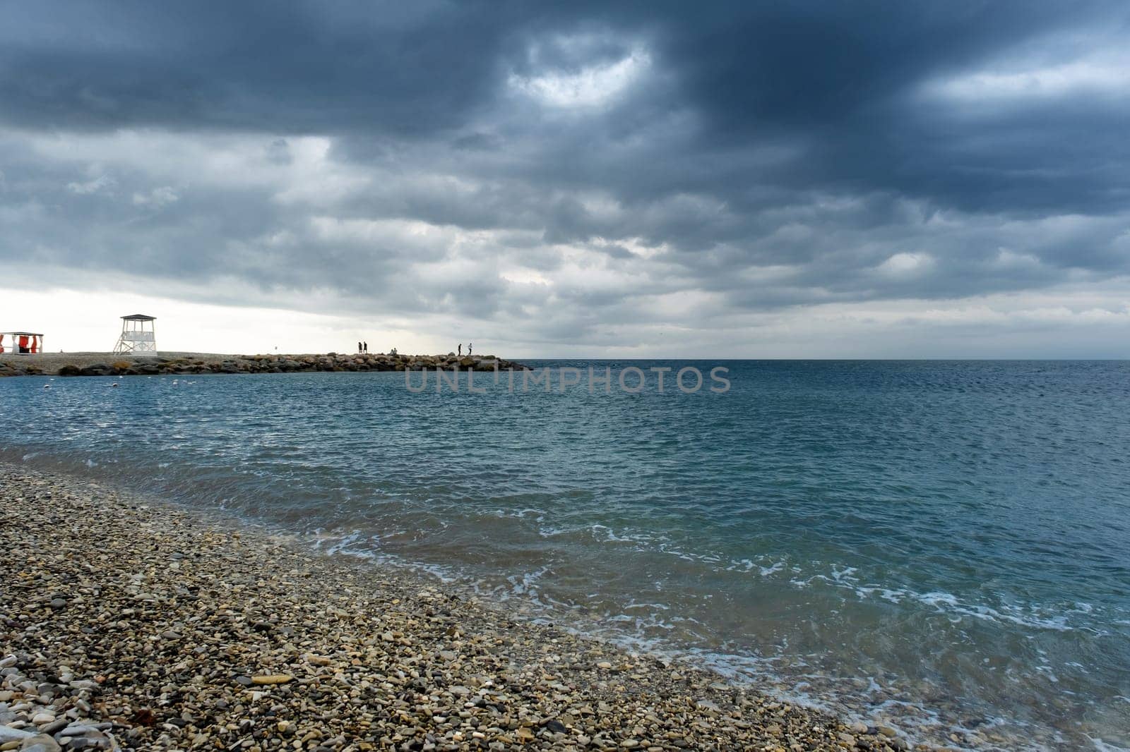 Scenic landscape of the beach and dark blue sea, cloudy sky before a thunderstorm by NataliPopova
