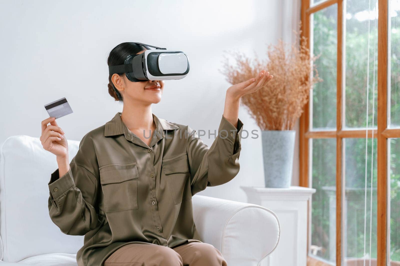 Young woman using virtual reality VR goggle at home for uttermost online shopping experience. The virtual reality VR innovation optimized for digital entertainment lifestyle.