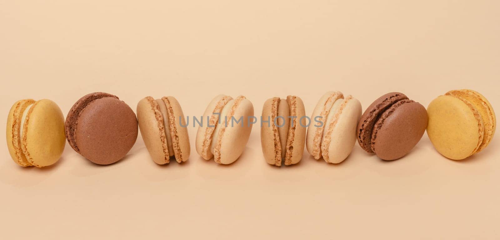 Chocolate macarons on a beige background, dessert