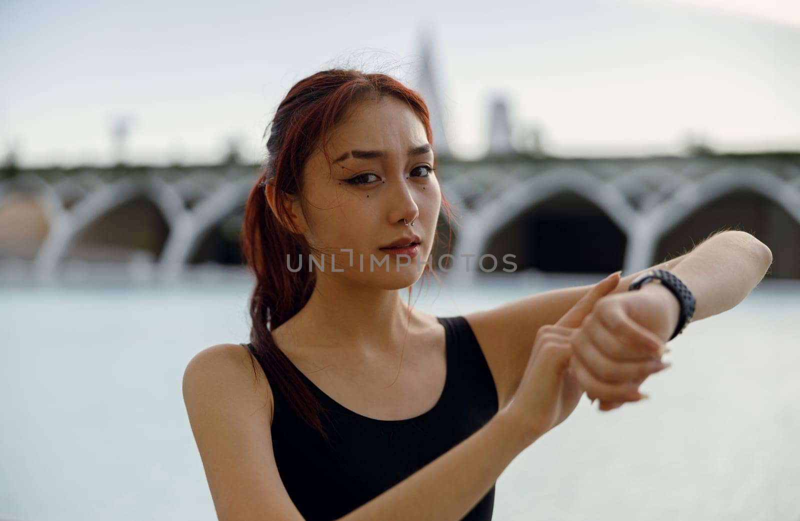 Young woman in sportswear looking on smartwatch before exercising. Outdoor sports in the morning by Yaroslav_astakhov