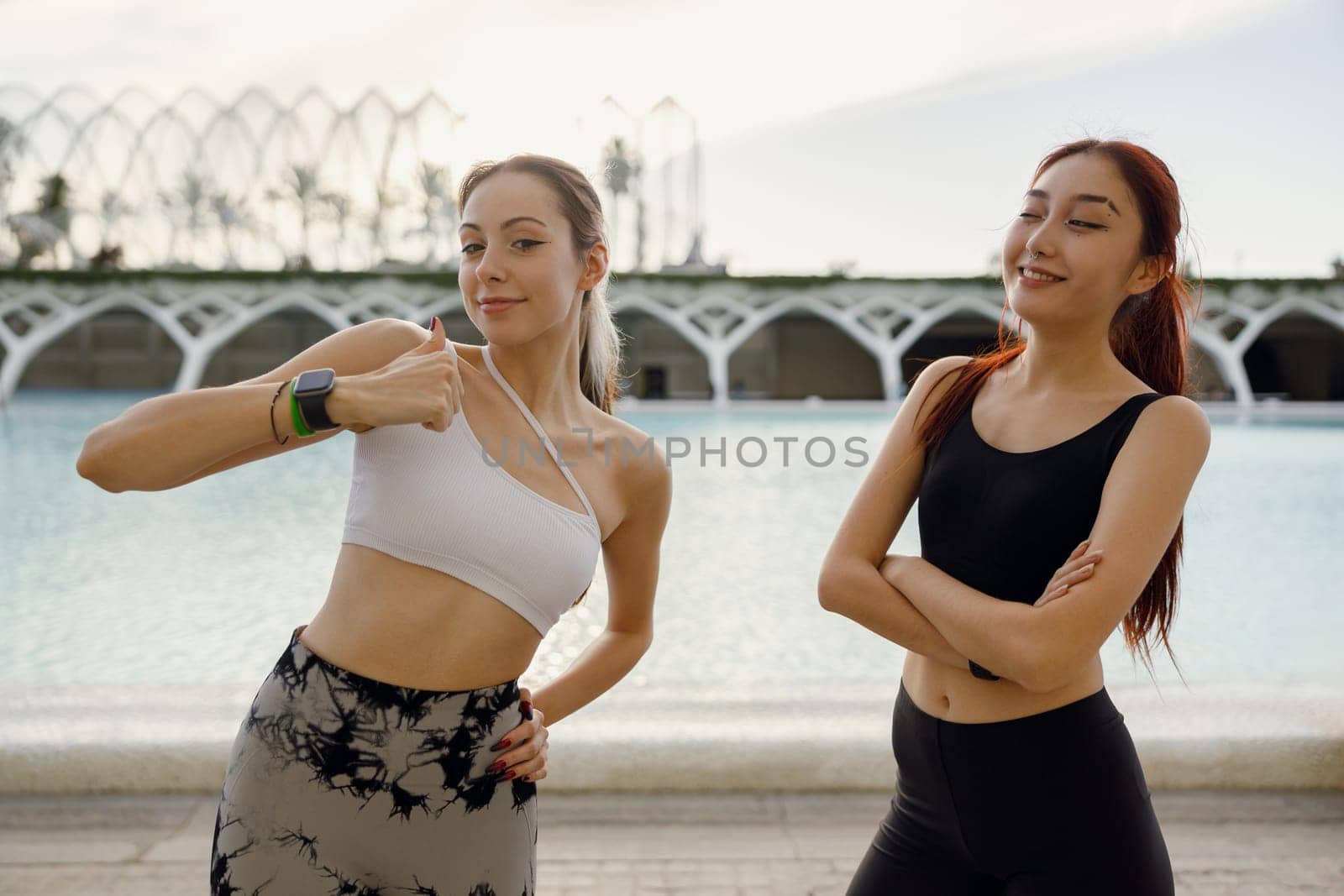 Young happy female sportswomen have a rest after morning jogging outdoors by Yaroslav_astakhov