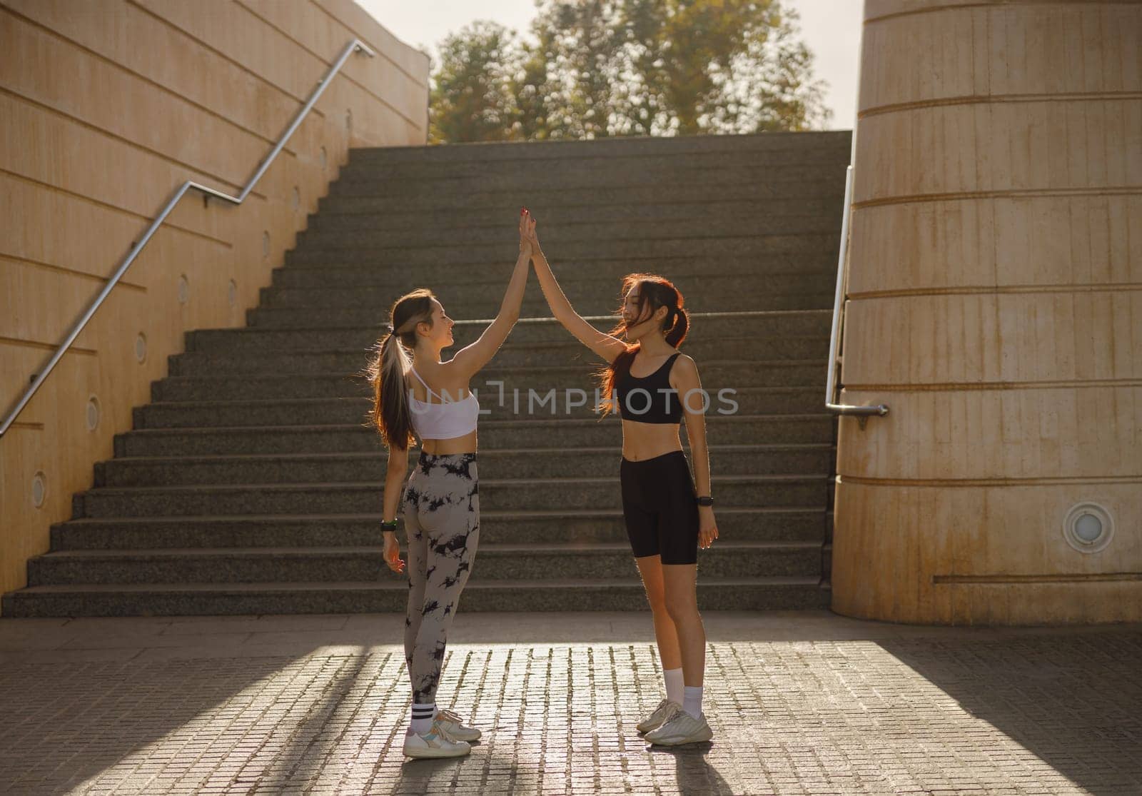 Sporty women greeting together outdoor doing gesture of shake hand after exercising by Yaroslav_astakhov