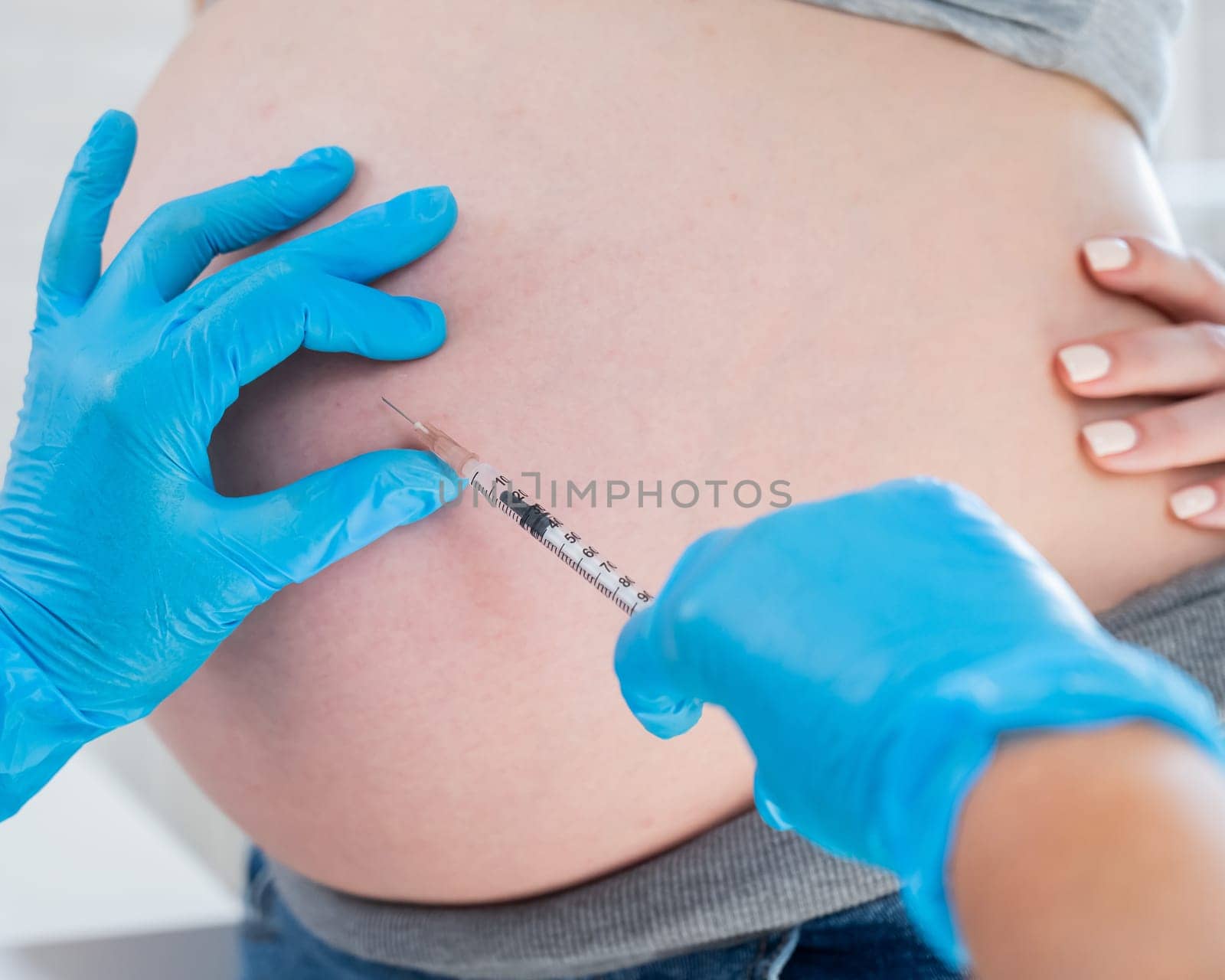 Doctor gives an injection in the stomach of a pregnant woman. by mrwed54