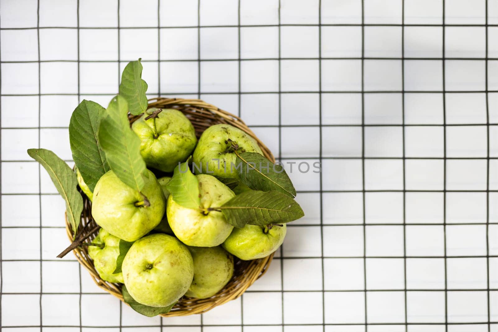 Top view a fresh green raw guava. Fruit with bright green bark and white pulp, sweet, crispy in a bamboo basket isolate on a white background