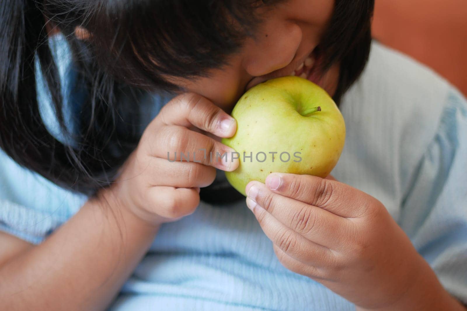 Girl biting and eating green apple .
