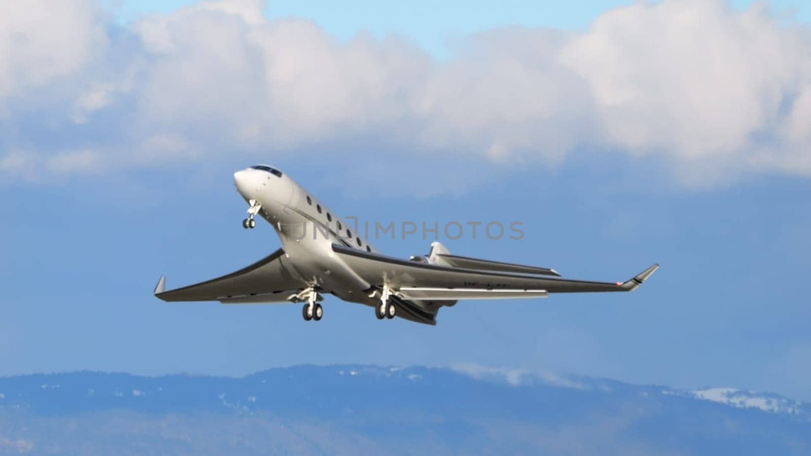 Payerne Switzerland January 15, 2024: Sleek private jet ascends with elegance against a backdrop of distant mountains and clear skies. High-end travel editorials with copy space. Gulfstream 650 OE-LTF