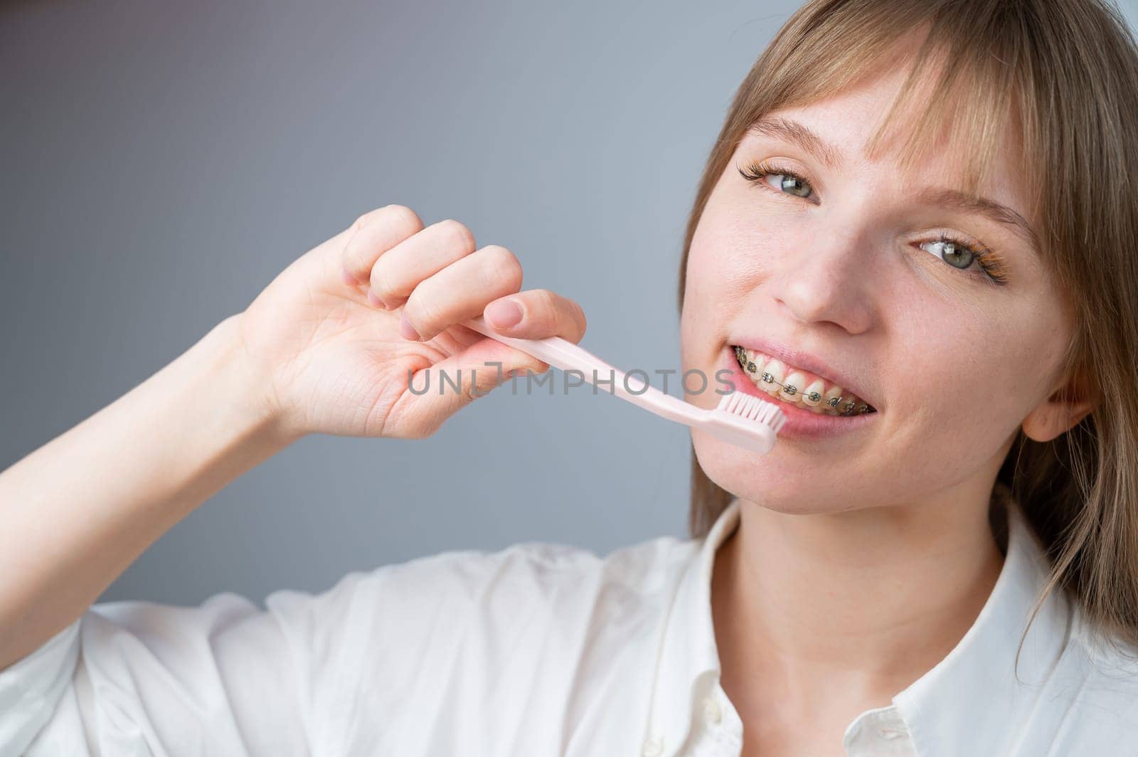 Portrait of a caucasian woman with braces on her teeth holding a toothbrush. by mrwed54