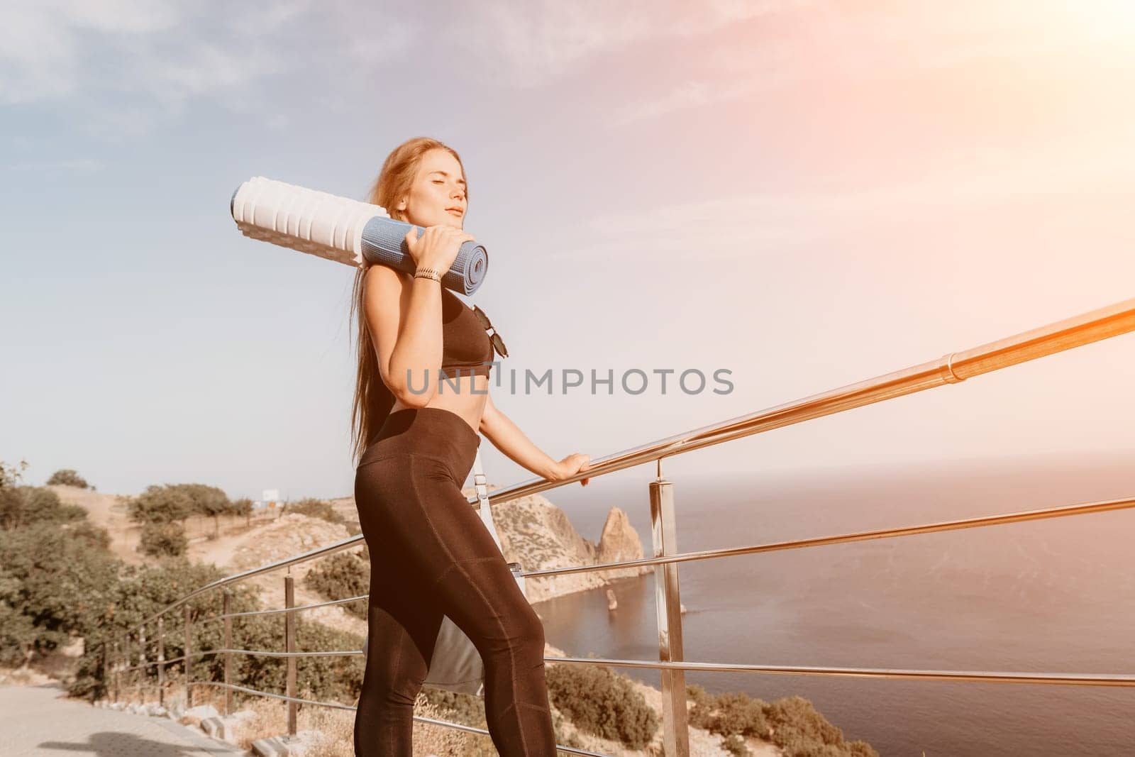 Fitness woman sea. Outdoor workout on yoga mat in park near to ocean beach. Female fitness pilates yoga routine concept. Healthy lifestyle. Happy fit woman exercising with rubber band in park.