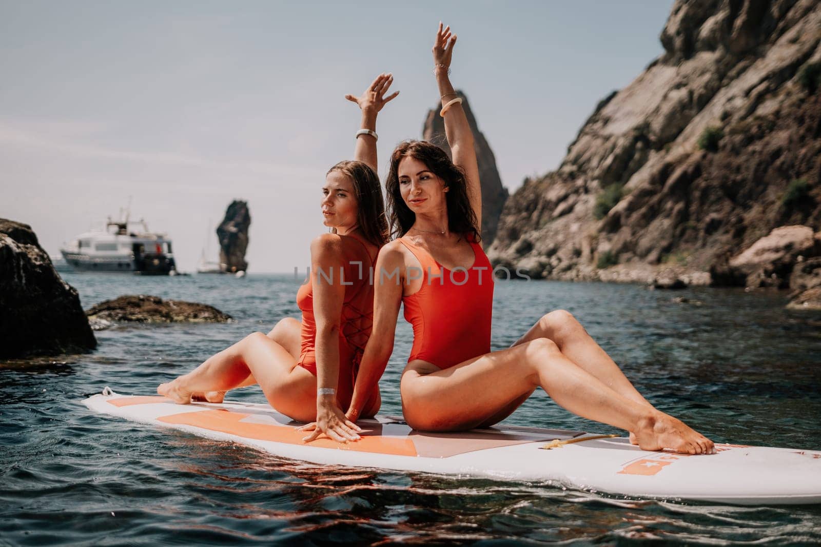 Woman sup yoga. Middle age sporty woman practising yoga pilates on paddle sup surfboard. Female stretching doing workout on sea water. Modern individual hipster outdoor summer sport activity