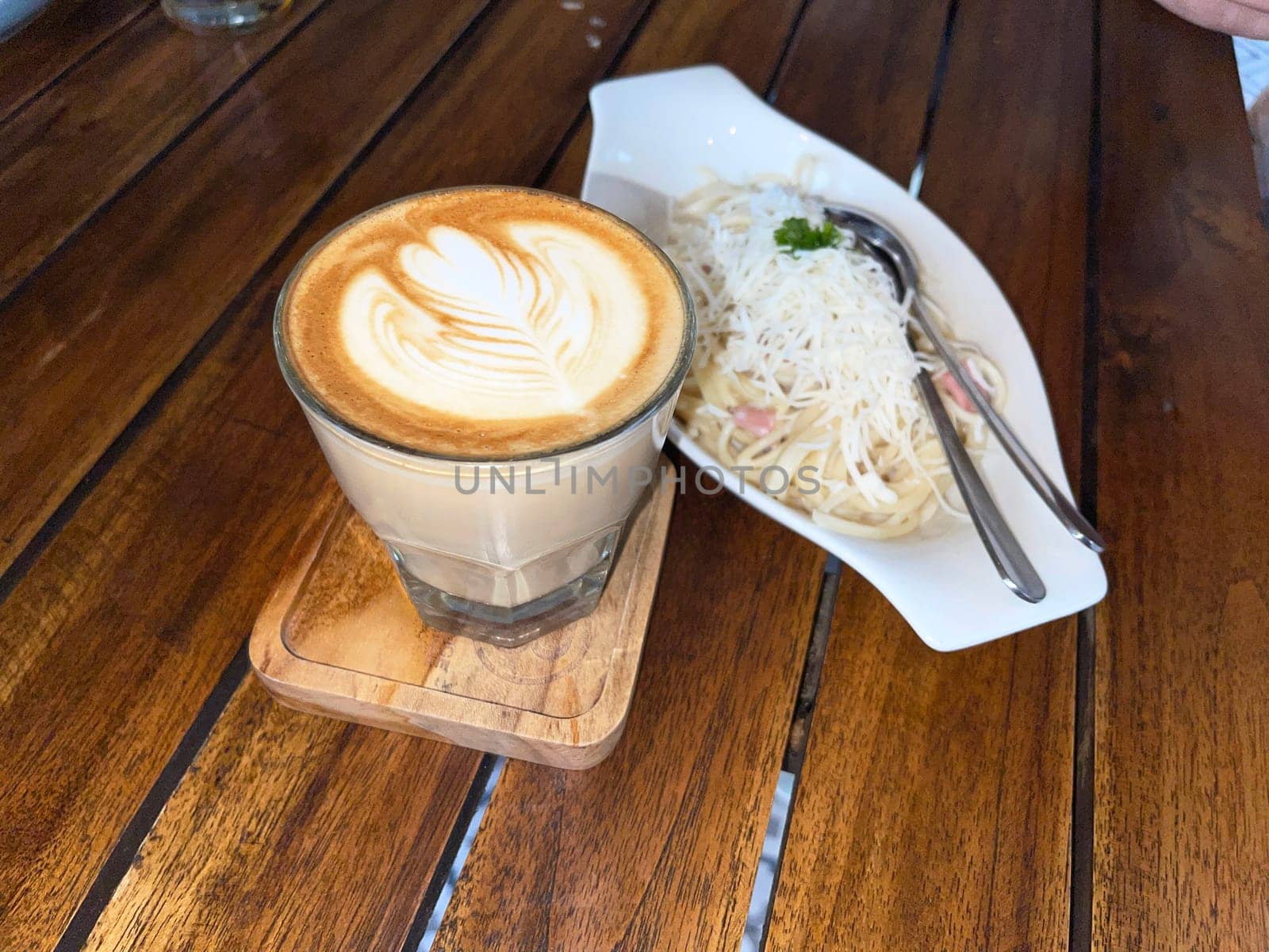 beautiful cup of cappuccino coffee with latte art and spaghetti alla carbonara in white plate with wooden space background