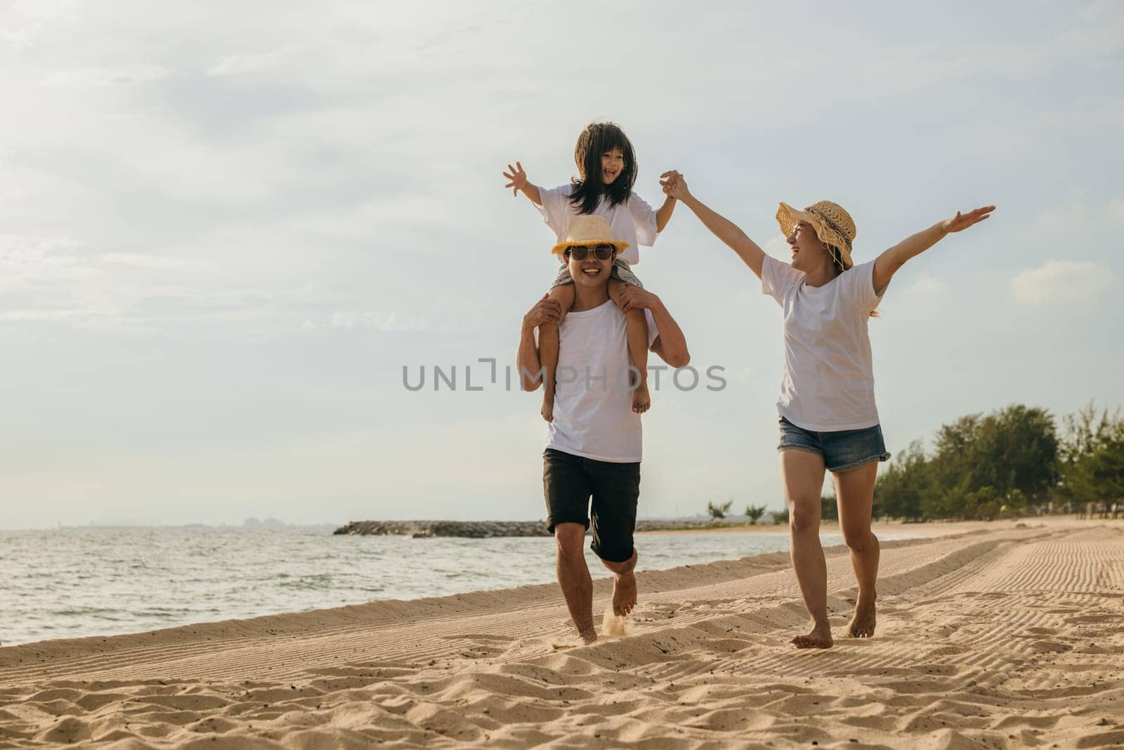 Road trips day. Happy family people having fun in summer vacation on beach, daughter riding on father back and mother running race at sand beach, enjoying road family trip playing together outdoor