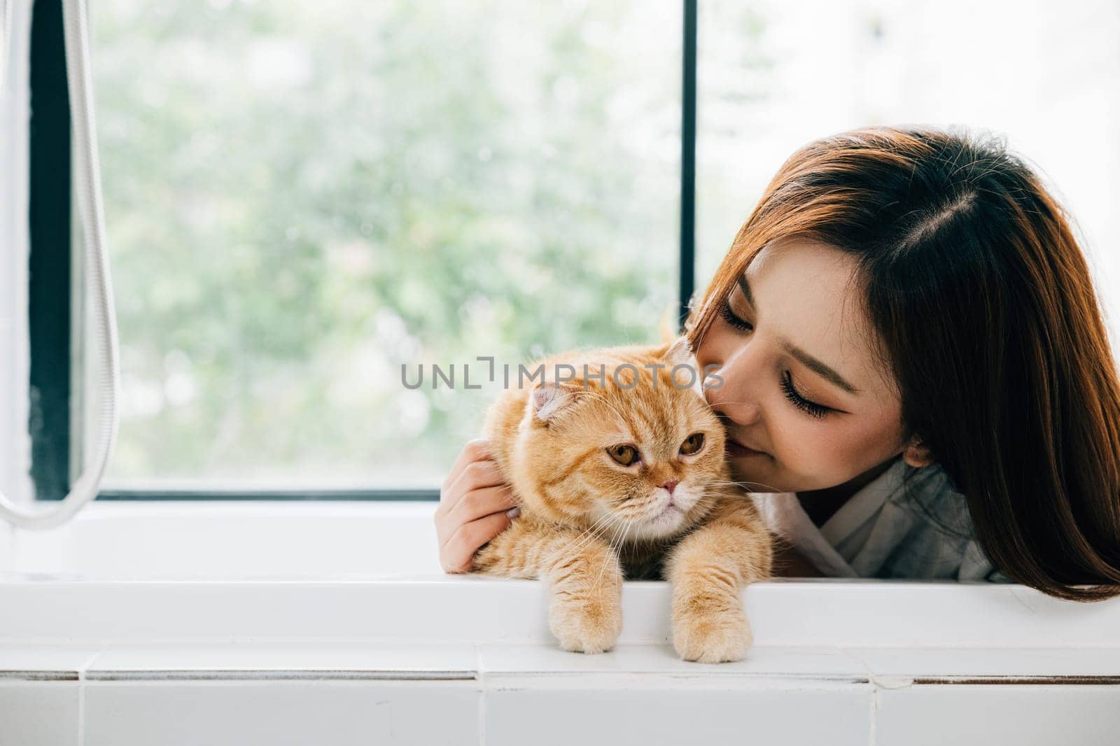 A beautiful bathroom portrait, An adult woman finds happiness in her bath as she holds her Scottish Fold cat, a perfect blend of owner-pet love and peaceful solitude. by Sorapop