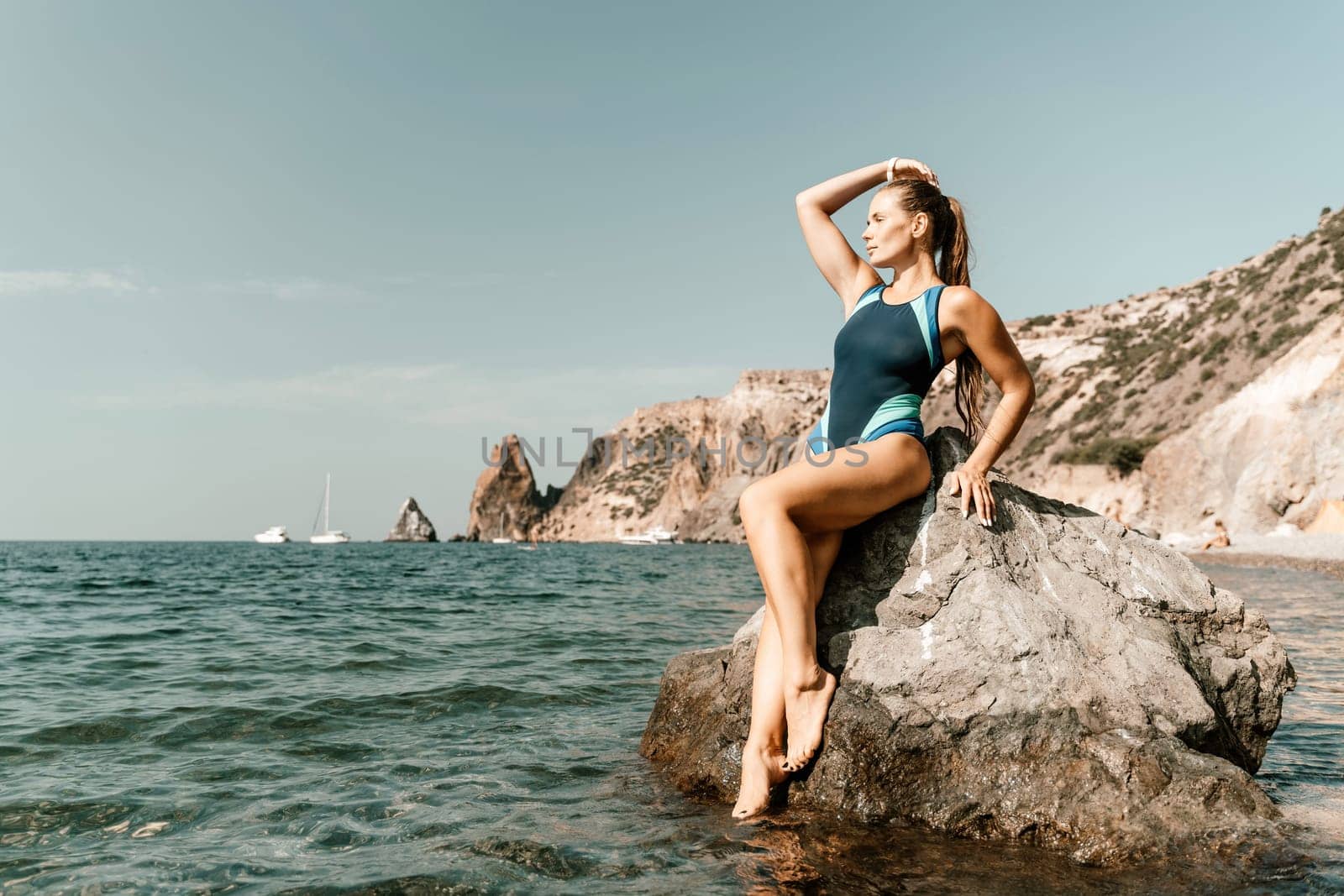 Woman beach vacation photo. A happy tourist in a blue bikini enjoying the scenic view of the sea and volcanic mountains while taking pictures to capture the memories of her travel adventure. by Matiunina