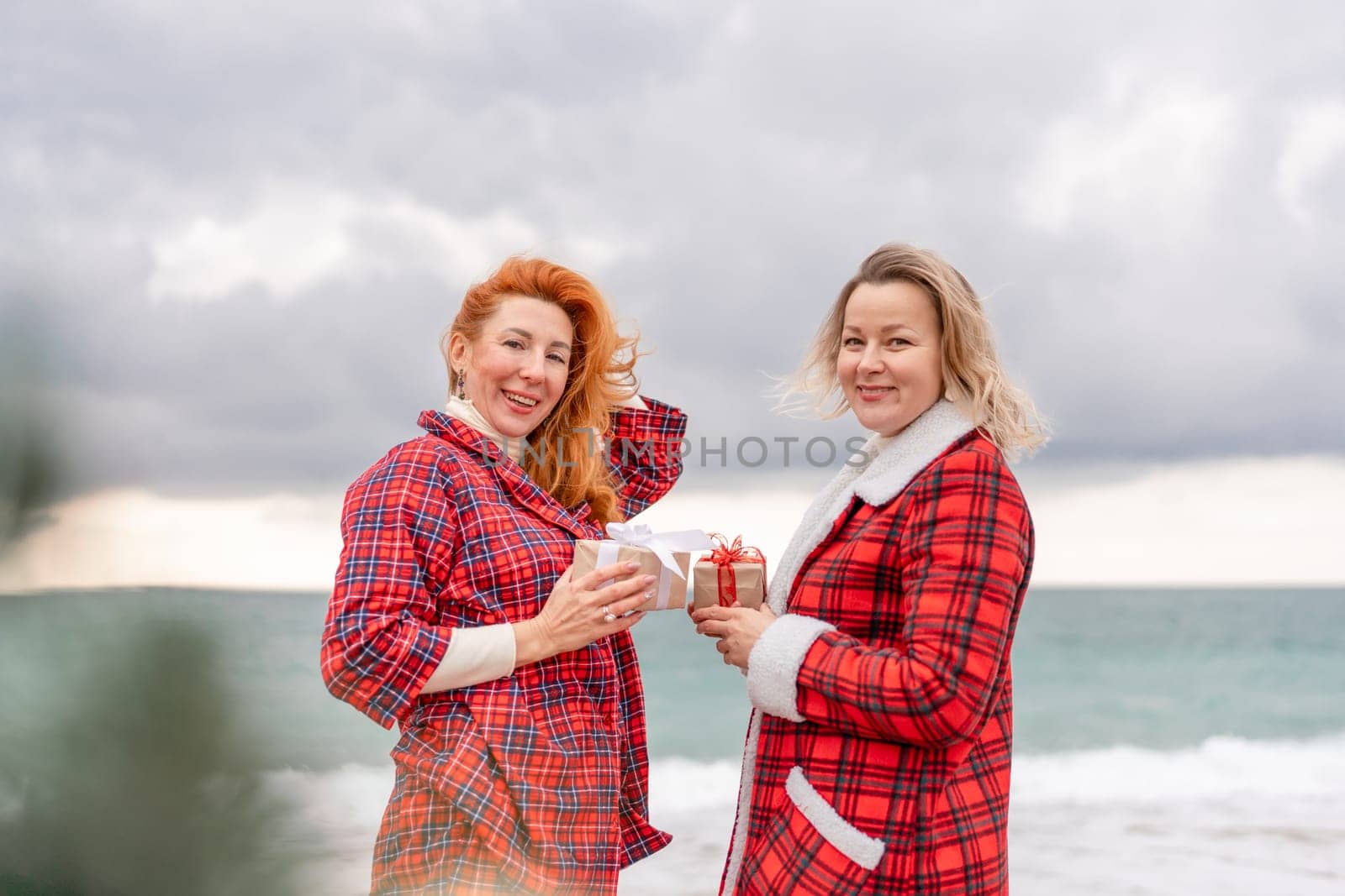 Sea two Lady in plaid shirt with a christmas tree in her hands enjoys beach. Coastal area. Christmas, New Year holidays concep.