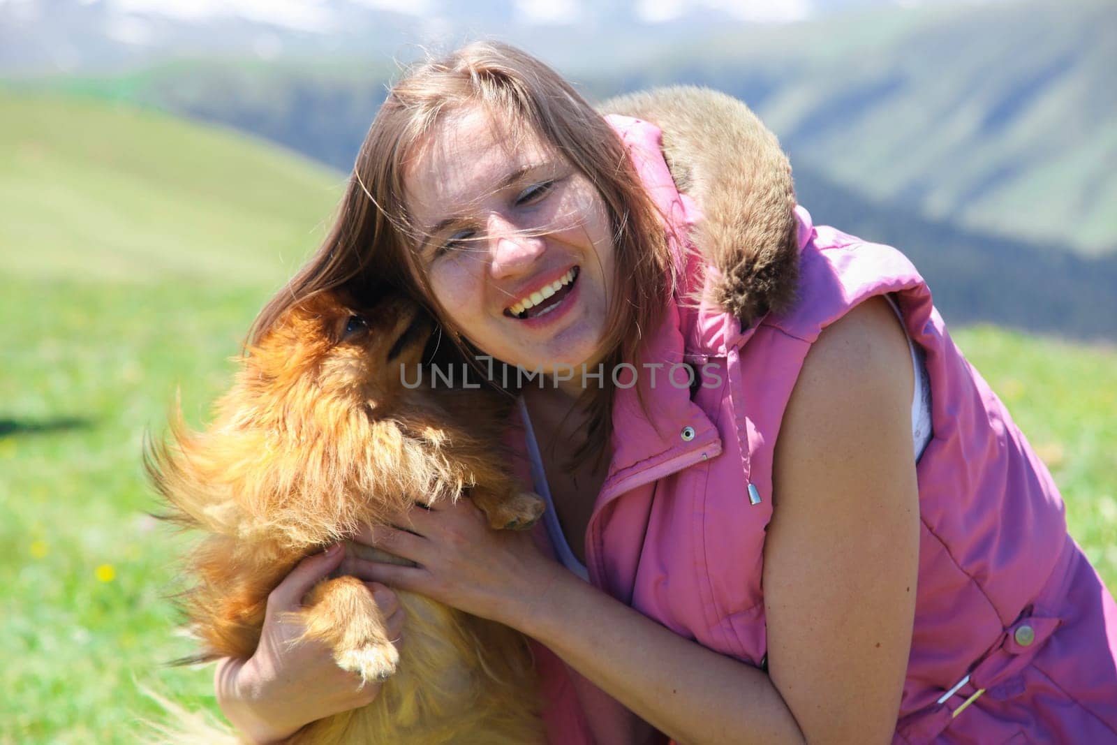 A small red dog (Pomeranian Spitz) licks a woman's face forcing her to laugh