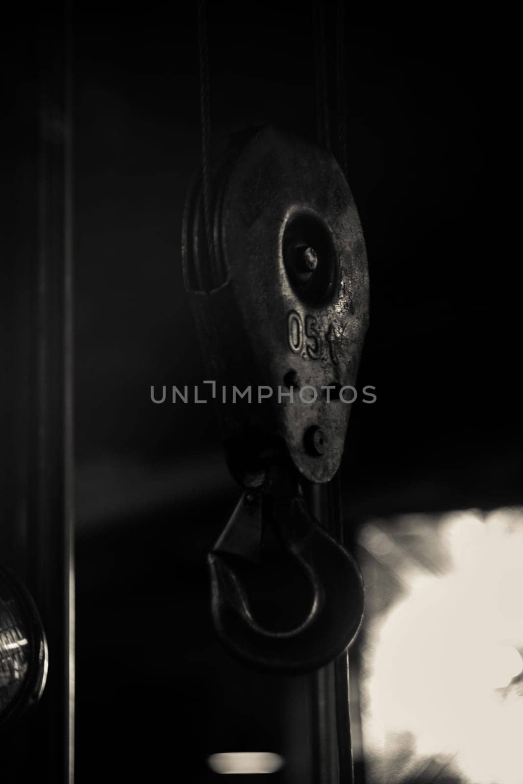 Metal hook from a crane against the background of a workshop. A piece of metal or other material, curved or bent back at an angle, for catching hold of or hanging things on.