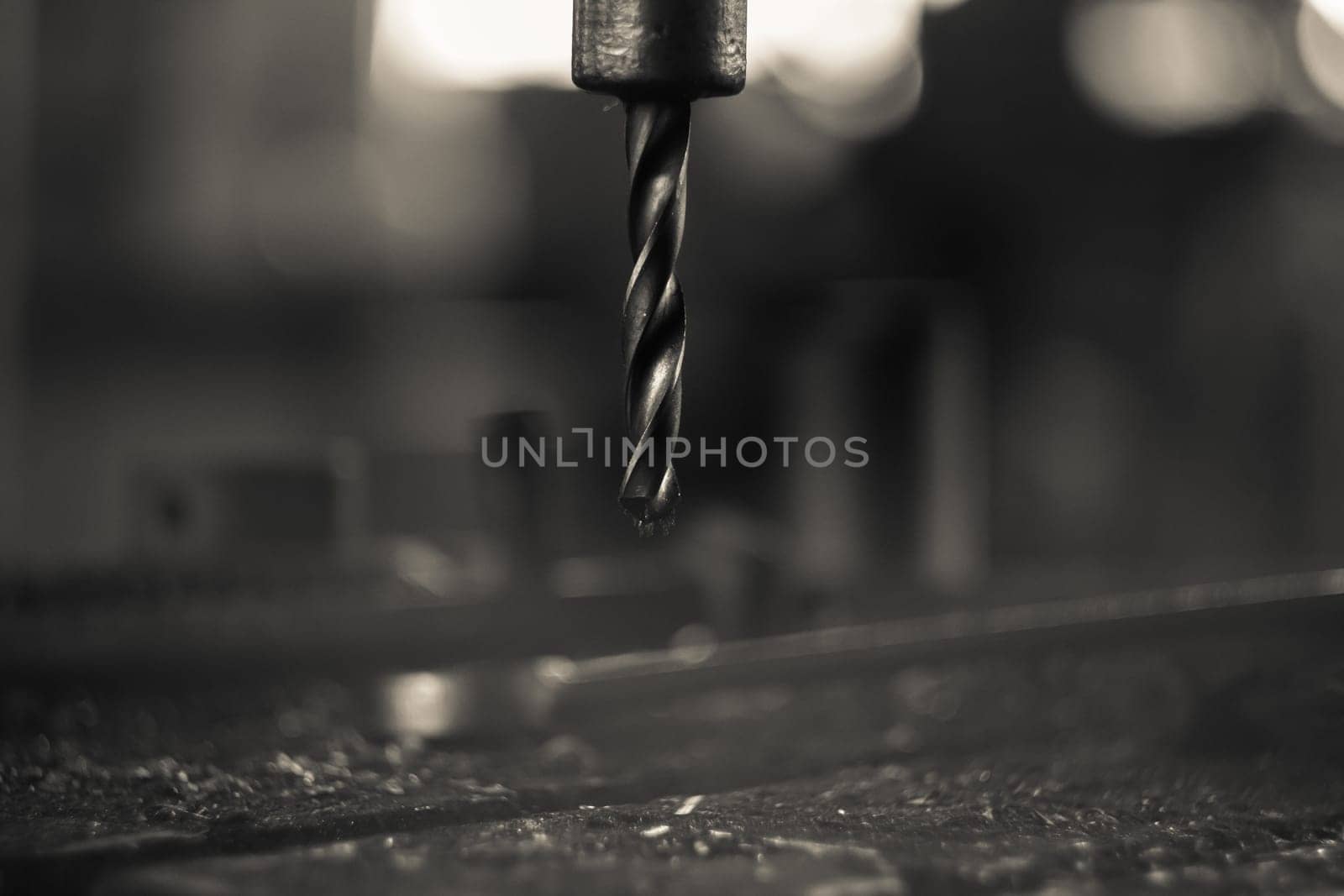 A part of a workbench with a metal drill and shavings on it