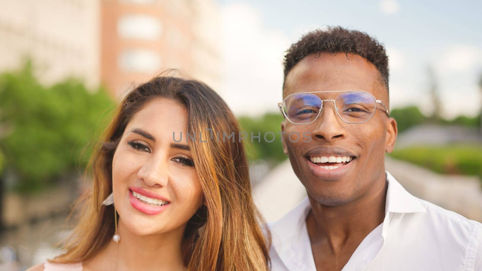 Multiethnic couple of a latina woman and a african man looking at the camera and smiling outdoors