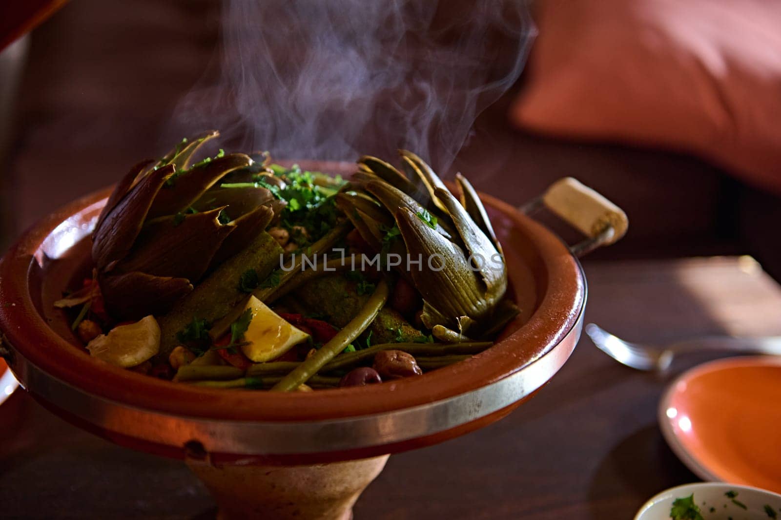 Close-up roasted vegetables in clay pot tagine with stem. Extreme closeup photography for food blogs and advertisings. Moroccan traditional food. Cultures. Traditions. Culinary. Crockery