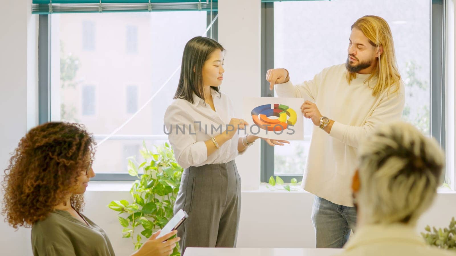 Man explaining an idea using a graphic during a multi-ethnic meeting in a coworking space