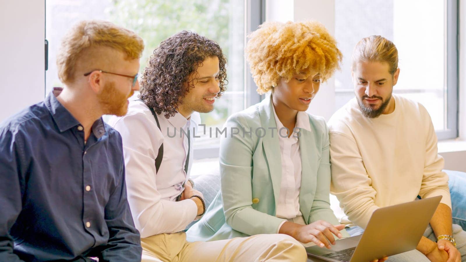 Woman using laptop while talking with colleagues in a coworking by ivanmoreno