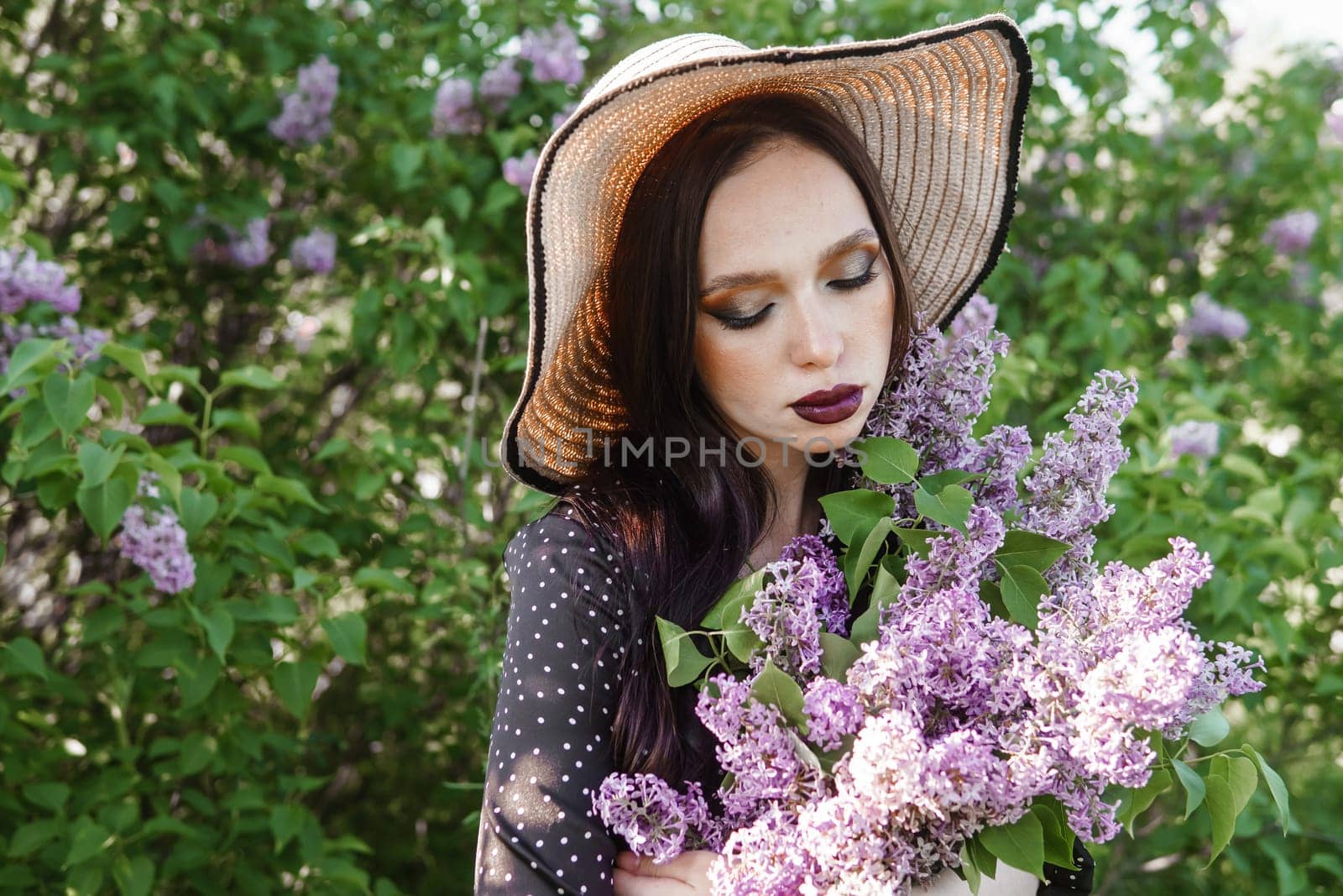 A fashionable girl with dark hair, a spring portrait in lilac tones in summer. Bright professional makeup