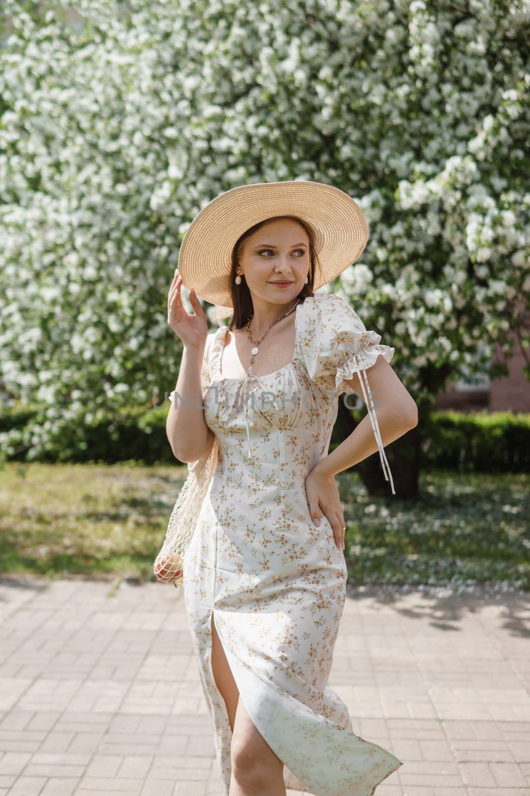 An attractive long-haired woman walks in the spring in the park of blooming apple trees. Spring portrait of a woman