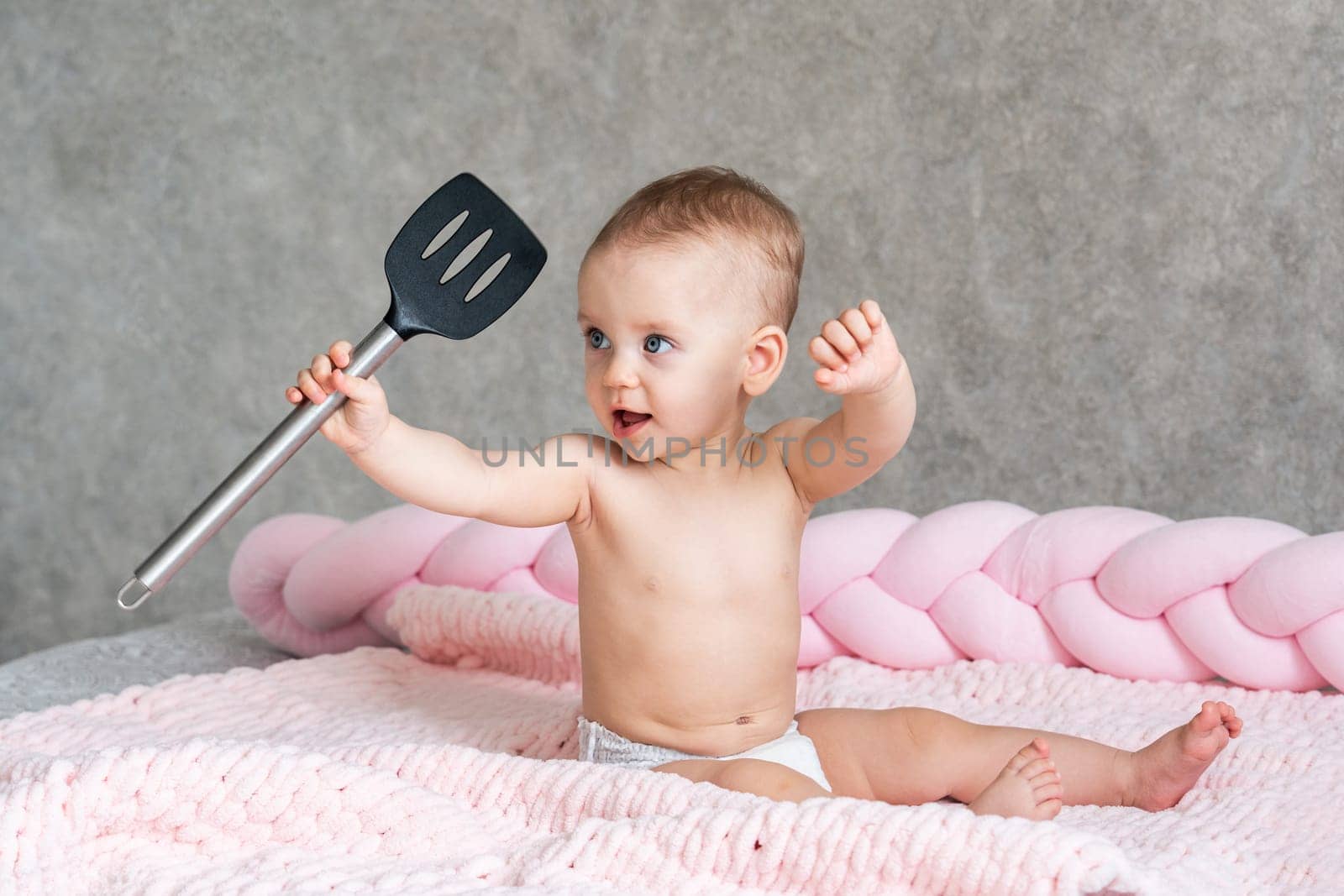 child plays with a kitchen spatula and has fun.